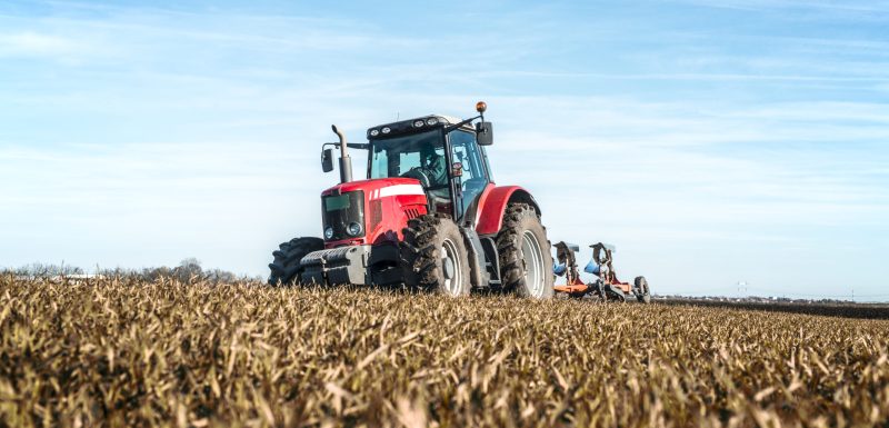 Tractor agricultural machine cultivating field.